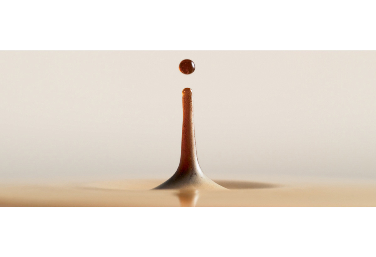 Στη φωτογραφία απεικονίζεται μια σταγόνα καφέ να πέφτει πάνω στο ρόφημα.