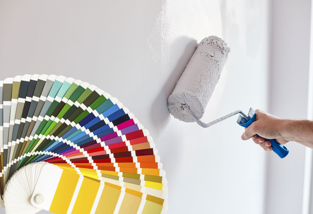 Παρουσιάζει κάποιον που βάζει ένα τοίχο και δίπλα φαίνεται ένα χρωματολόγιο σε σχήμα βεντάλιας