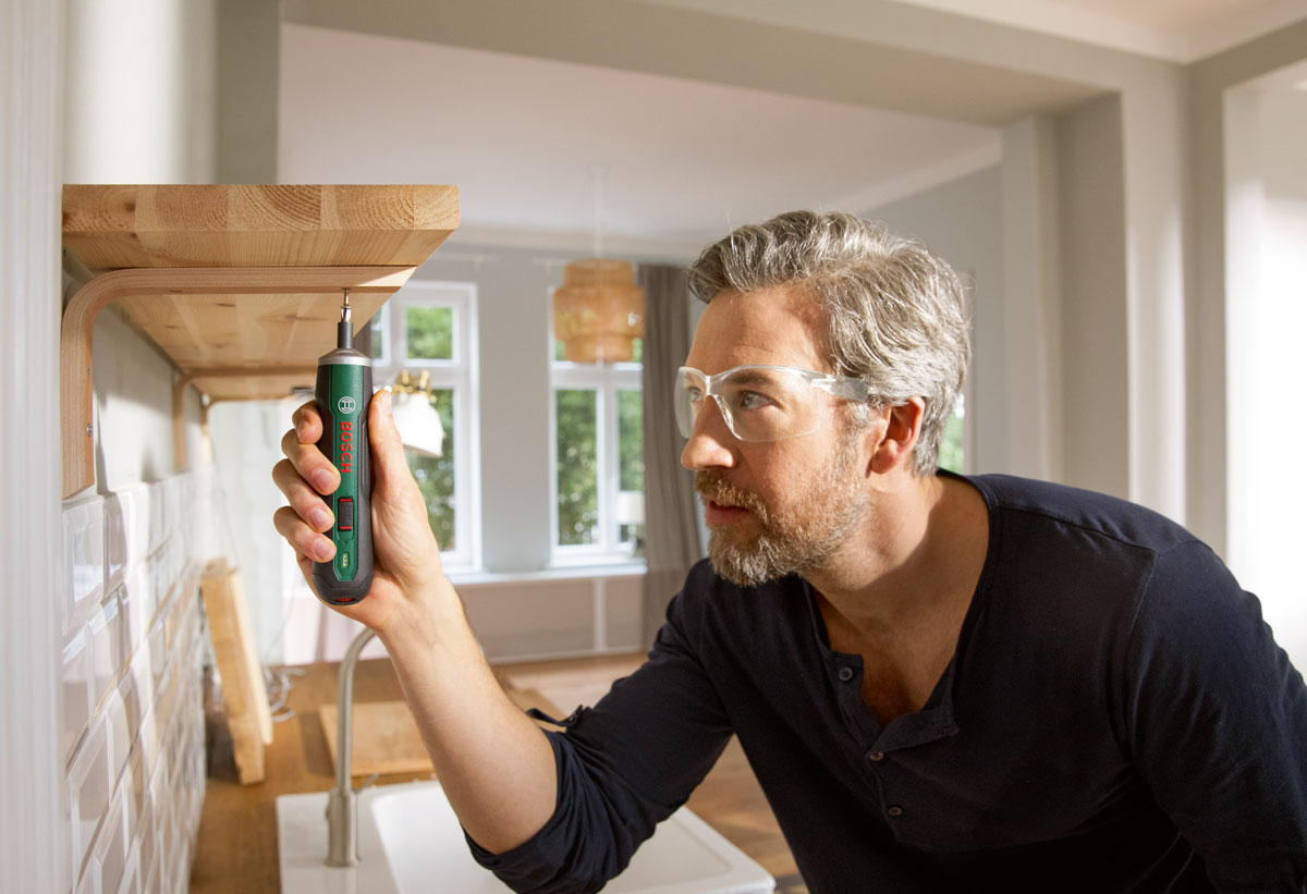 Άντρας βιδώνει ένα έπιπλο με το κατσαβίδι Bosch Pushdrive.