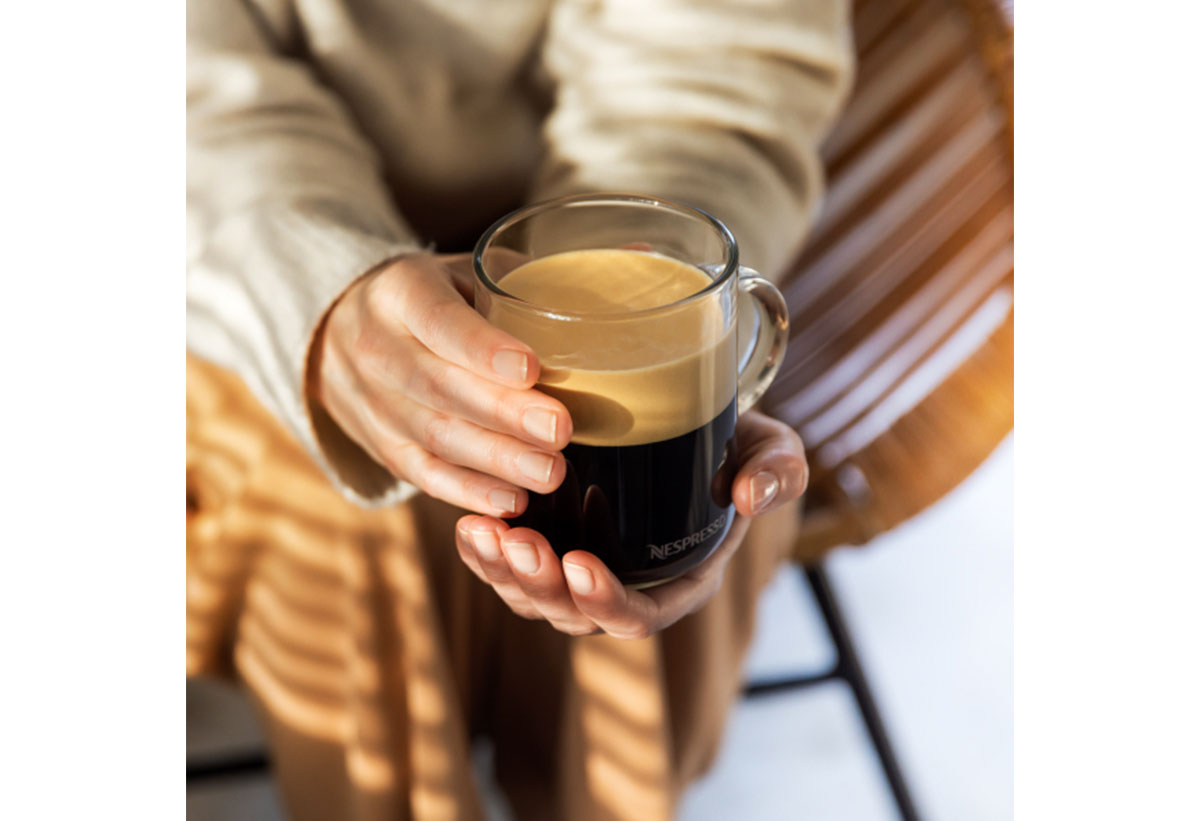 Μια γυναίκα κρατάει ένα φλυτζάνι Nespresso με καφέ